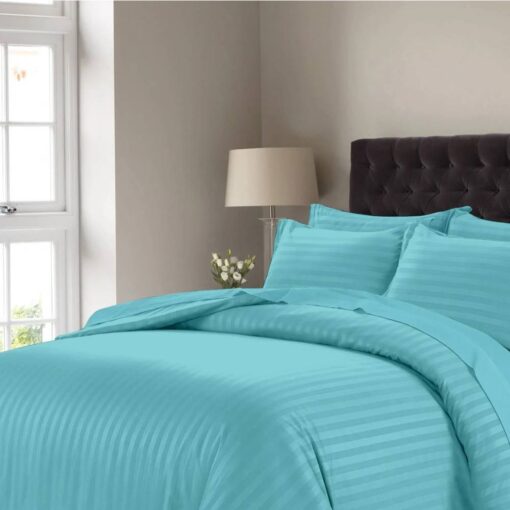 Pastel striped comforter set with matching pillow shams on a bed with a dark tufted headboard in a modern bedroom setting.