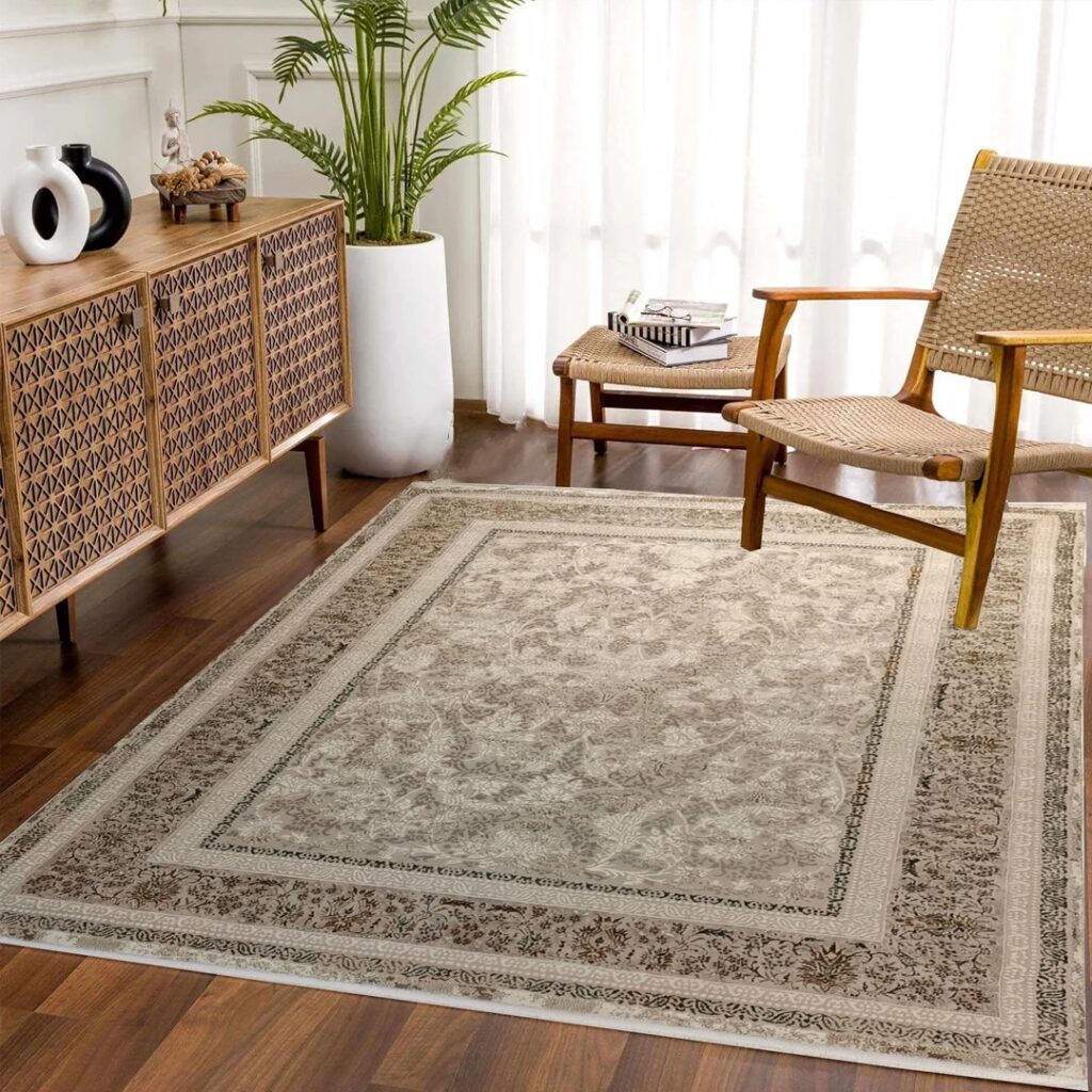 A chic room featuring a neutral-toned patterned carpet, a woven wooden armchair, a matching ottoman, and a decorative sideboard with intricate designs. The space is enhanced by natural light and a lush potted plant for a warm, inviting ambiance